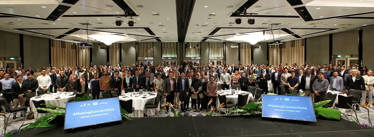 Large group of people in a conference room, #MakingConnections on screens.